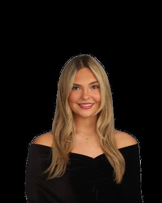 Woman with long blonde hair wearing an off-shoulder black top, smiling against a black background